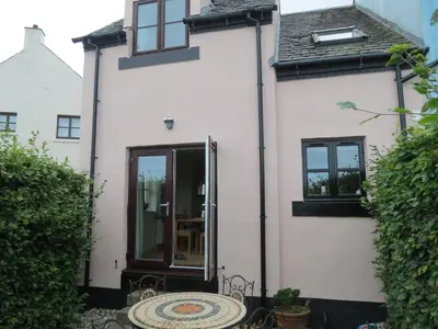 a white house with a patio in front of it at Morvern Cottage in Craobh Haven