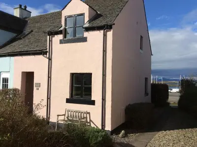 a white house with a bench in front of it at Morvern Cottage in Craobh Haven