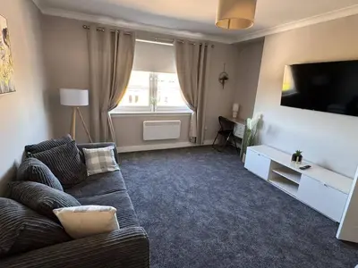 a living room with a couch and a flat screen tv at 3 bedroom Falkirk flat in Falkirk