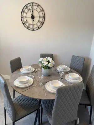 a dining room table with chairs and a clock on the wall at 3 bedroom Falkirk flat in Falkirk