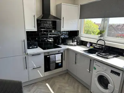a kitchen with white cabinets and a washer and dryer at 3 bedroom Falkirk flat in Falkirk