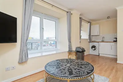 a living room with a table and a kitchen at Glasgow Apartment near Hydro & SECC, Finnieston in Glasgow