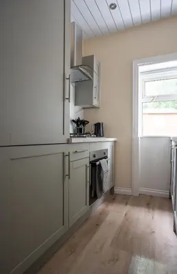 a kitchen with white cabinets and a sink and a window at Curtis Apartment in Glasgow