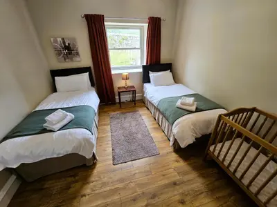 two twin beds in a room with a window at Balmory Stables North, luxury stable conversion in Ascog