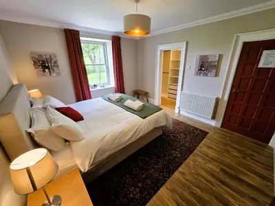 a bedroom with a large bed and a window at Balmory Stables North, luxury stable conversion in Ascog