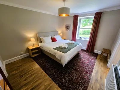 a bedroom with a large bed and a window at Balmory Stables North, luxury stable conversion in Ascog