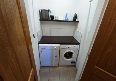 a small laundry room with a washer and dryer at Balmory Stables South - luxury stable conversion in Ascog