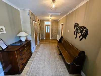 a hallway with a wooden dresser and a horse on the wall at Balmory Stables South - luxury stable conversion in Ascog