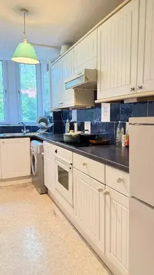 a kitchen with white cabinets and a black counter top at Glasgow One Bedroom Flat close to city centre and all amenities in Glasgow