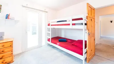 a bedroom with two bunk beds with red sheets at Stag's View Lodge in Edinburgh