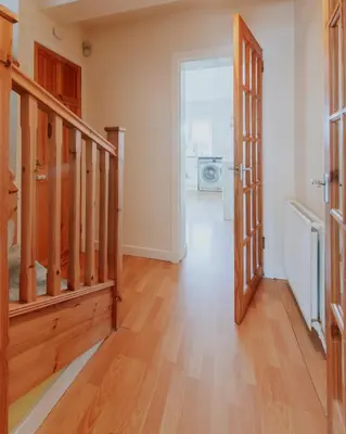 an empty hallway with a wooden staircase and a door at Stag's View Lodge in Edinburgh