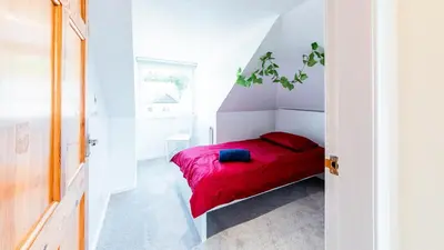 a small bedroom with a bed with a red blanket at Stag's View Lodge in Edinburgh