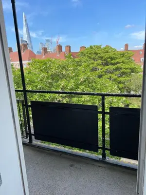 a balcony with a view of a tree and buildings at Flat in London Bridge in Moffat
