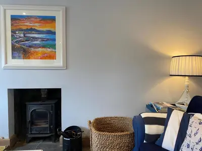 a living room with a fireplace and a picture on the wall at Smithy House in Crinan