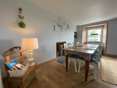 a dining room with a table and chairs and a window at Smithy House in Crinan