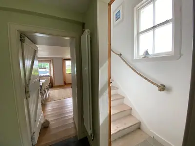 a hallway with stairs and a window in a house at Smithy House in Crinan