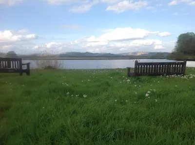 two benches sitting in the grass near a lake at Smithy House in Crinan