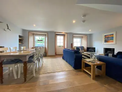 a dining room and living room with a table and chairs at Smithy House in Crinan