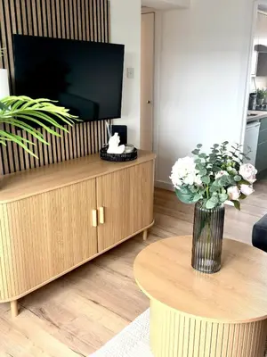 a living room with a television and a vase of flowers at Almondvale Apartment in Livingston