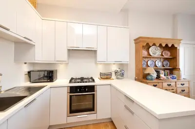 a kitchen with white cabinets and a stove top oven at Edinburgh Stockbridge Charm Apartment in Edinburgh
