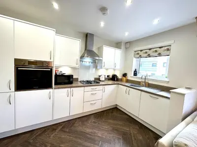 a kitchen with white cabinets and a stove top oven at The Clyde Retreat, 2 Bedrooms in Glasgow