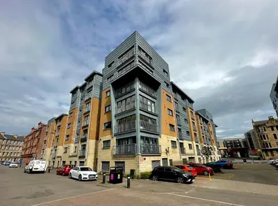 a tall building with cars parked in a parking lot at The Clyde Retreat, 2 Bedrooms in Glasgow