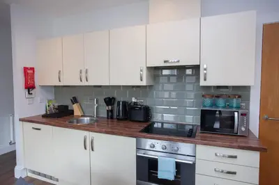 a kitchen with white cabinets and a sink and a microwave at Stylish 3rd Floor Flat in Historic Merchant City in Glasgow