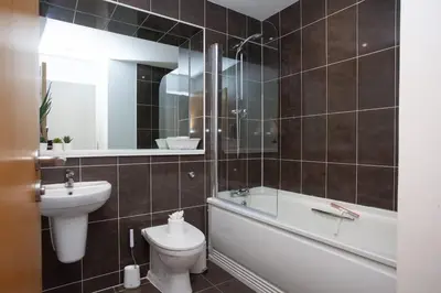 a bathroom with a sink and a toilet and a bath tub at Stylish 3rd Floor Flat in Historic Merchant City in Glasgow