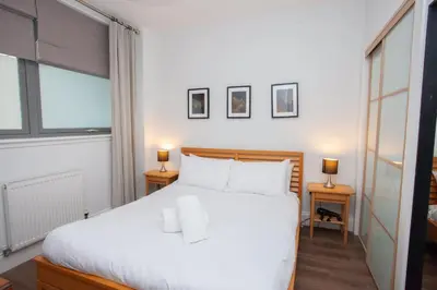 a bedroom with a large white bed with two lamps at Stylish 3rd Floor Flat in Historic Merchant City in Glasgow