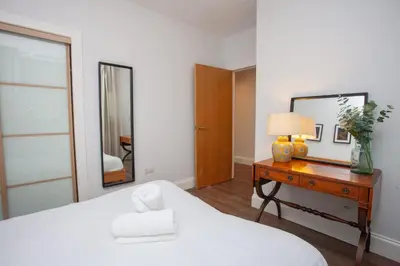 a bedroom with a bed and a table with a mirror at Stylish 3rd Floor Flat in Historic Merchant City in Glasgow