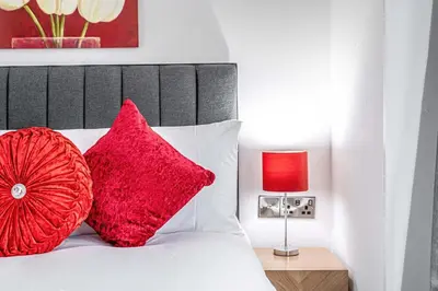 a bedroom with a bed with red pillows and a lamp at Super Prime The City Residence in Dunfermline