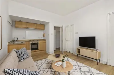 a living room with a couch and a table and a kitchen at Haymarket Edinburgh Flat Sleeps 4 in Edinburgh