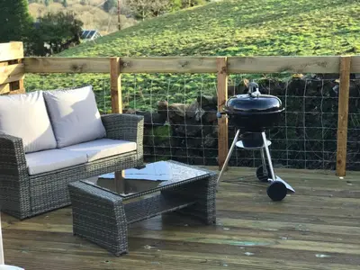 a grill sitting on a deck with a chair and a grill at Queensland Holiday Park - Glamping in South West Scotland in Barrhill