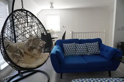 a swing chair and a blue couch in a living room at Detached Home in Bishopton in Bishopton