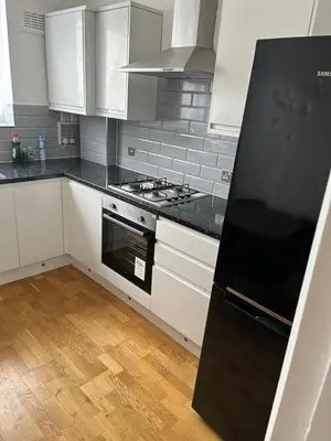 a kitchen with white cabinets and a black stove top oven at Flat in Moffat
