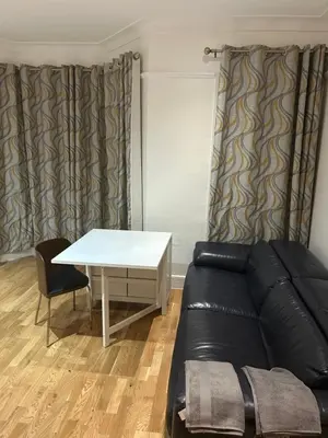 a living room with a black leather couch and a table at Flat in Moffat