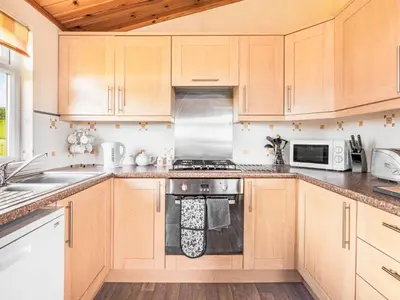 a kitchen with wooden cabinets and a stove top oven at Chalet Loch Side Lodge 5 by Interhome in Kinross