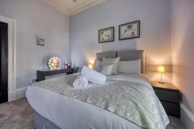 a bedroom with a large white bed with two lamps at The Burnbank Experience in Glasgow