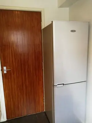 a refrigerator next to a wooden door in a room at Glasgow Property New City Rd in Glasgow