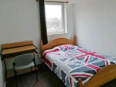 a bedroom with a bed and a desk and a window at Glasgow Property New City Rd in Glasgow