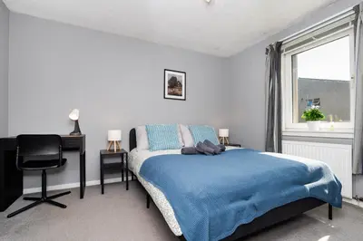 a bedroom with a bed and a desk and a window at 2 Bedroom Flat - Free Parking- by Holiday Homes in Clydebank