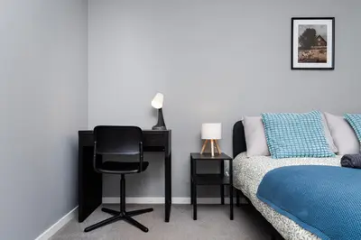 a bedroom with a desk and a chair next to a bed at 2 Bedroom Flat - Free Parking- by Holiday Homes in Clydebank