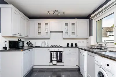 a white kitchen with white cabinets and appliances at 2 Bedroom Flat - Free Parking- by Holiday Homes in Clydebank