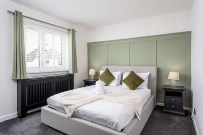 a bedroom with a large white bed with two tables at No15 Ellis House - Donnini Apartments in Kilmarnock