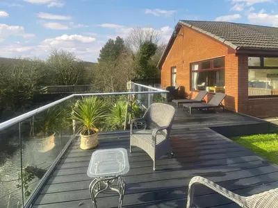 a deck with chairs and tables on a house at Riverside Cottage in Lamlash