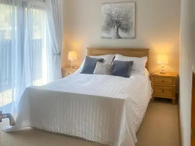 a white bed with blue pillows in a bedroom at Riverside Cottage in Lamlash