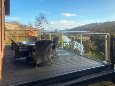 a deck with chairs and a table with a view at Riverside Cottage in Lamlash
