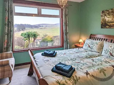 a bedroom with a bed with a large window at Bendhu in Mill of Fortune