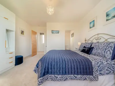 a bedroom with a blue bed and a chandelier at Hydee House in Dumfries