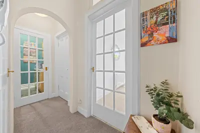 a hallway with white walls and doors and a plant at Cosy 1 Bedroom Apartment next to Fountain Park - Edinburgh in Edinburgh